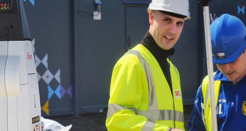 Two construction workers on construction site with Leica iCON robotic total station